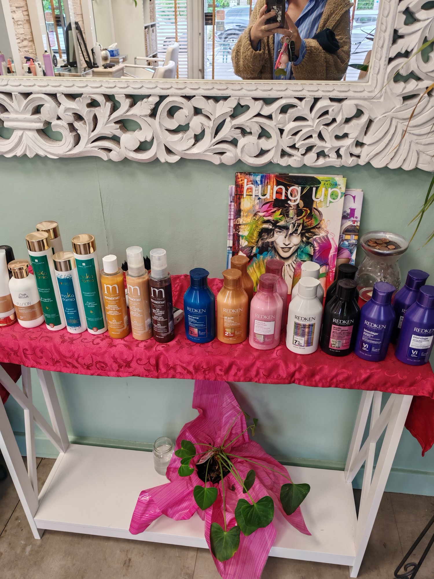 Présentoir de produits professionnels (Redken, M:N) sur fond vert sauge